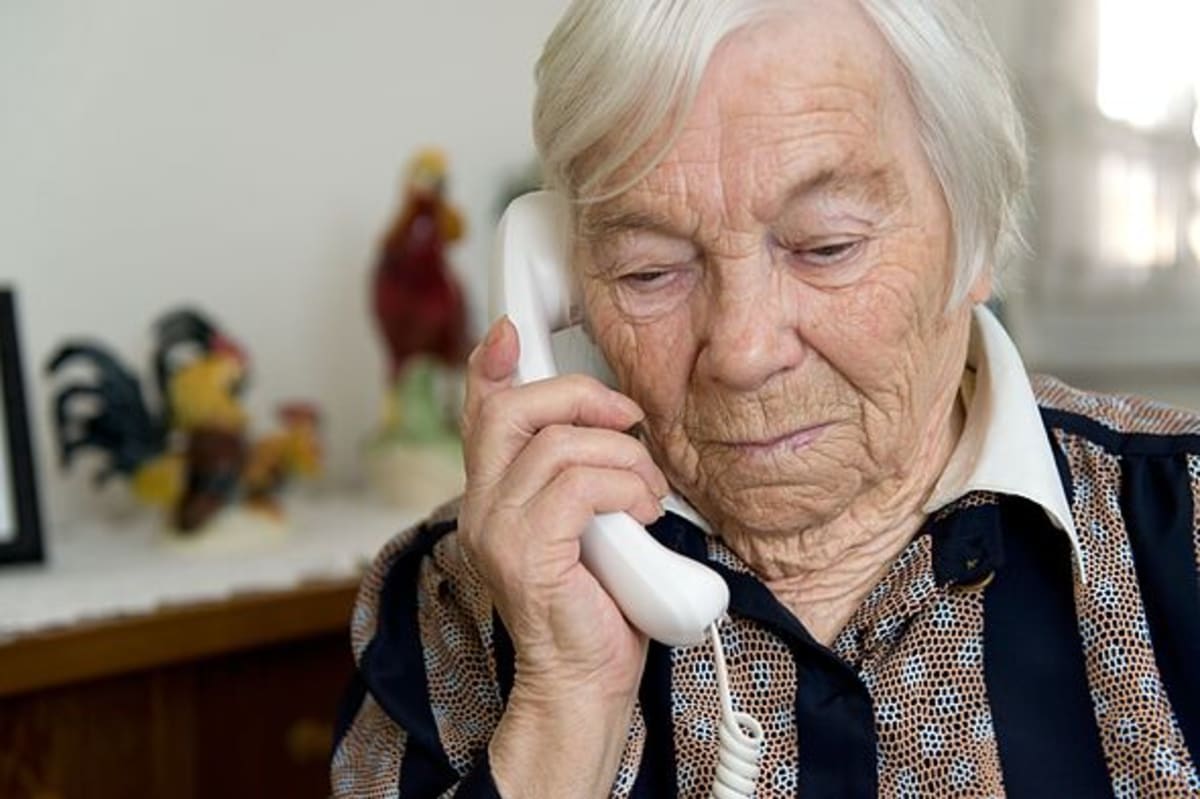 Grandma is holding a phone in hand and looks sad