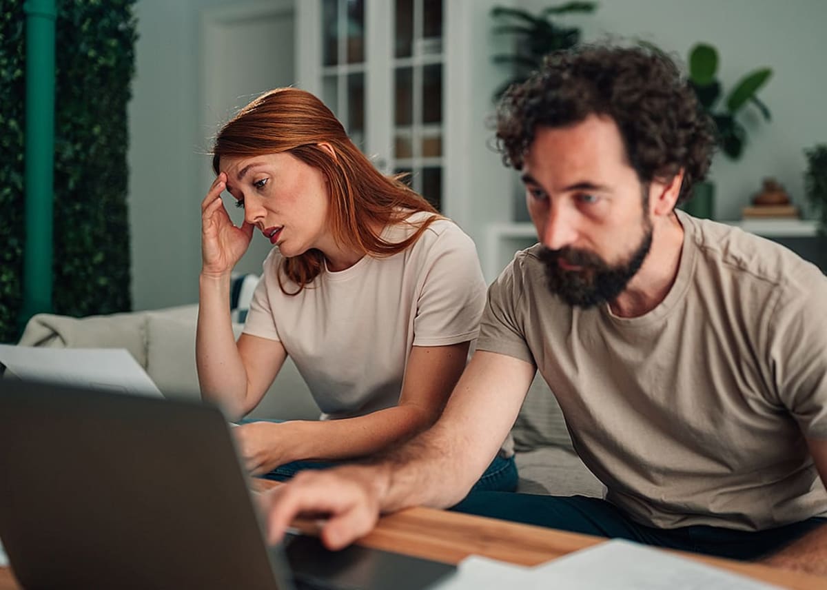 A couple at home feeling worried and stressed while calculating expenses. - Zamrznuti tonovi // Shutterstock